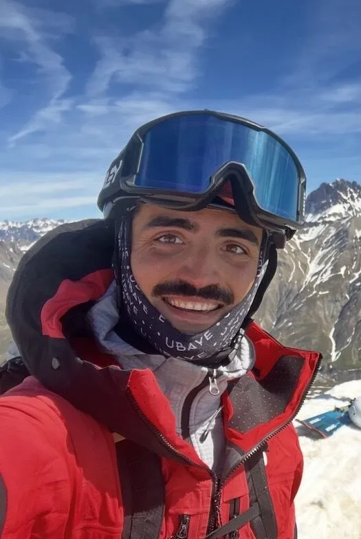 Andrea Murisasco in vetta, con maschera e giacca da sci alpinismo